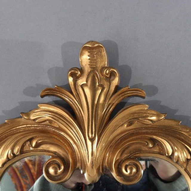 An antique French Louis XIV style wall mirror, crafted circa 1930, presents a magnificent example of Rococo Revival...