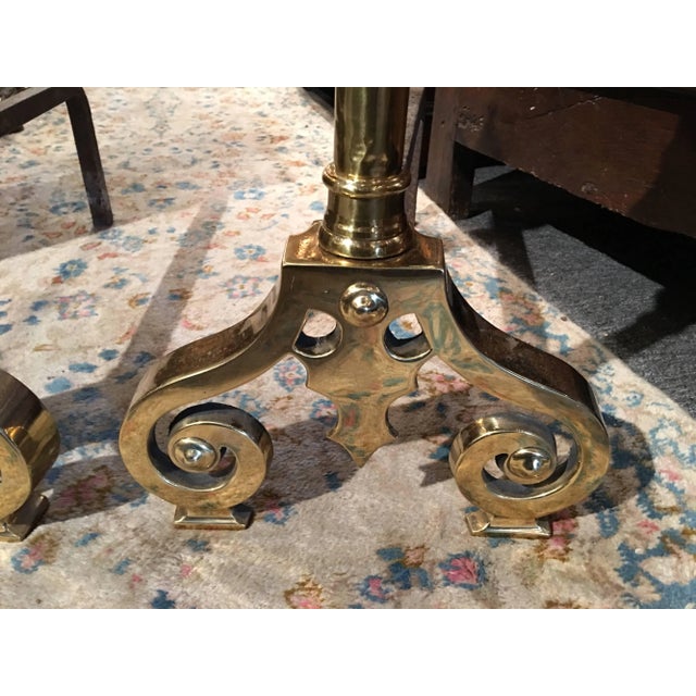 Pair of polished brass chenets or andirons with decorative scrolls and towering finials, 19th century.