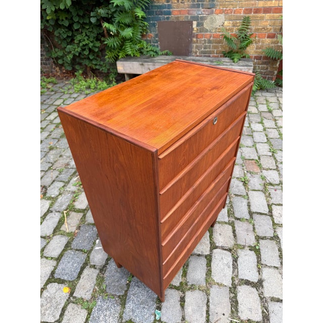 This Danish teak chest of drawers from the 1960s combines timeless mid-century minimalism with practical storage for...