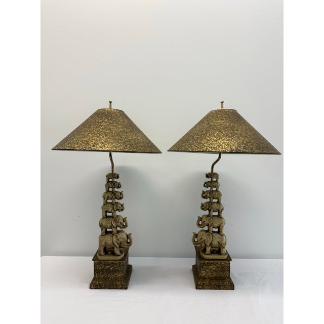 A charming and highly decorative pair of vintage elephant table lamps featuring whimsical stacked elephant columns rising...