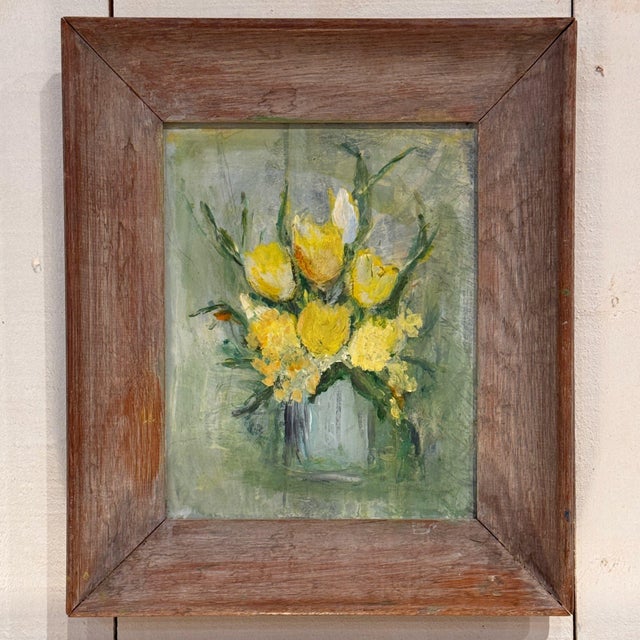 Still life of yellow flowers in a vase by Diana Heiskell, loosely painted against a soft green ground, in a wide wood frame.