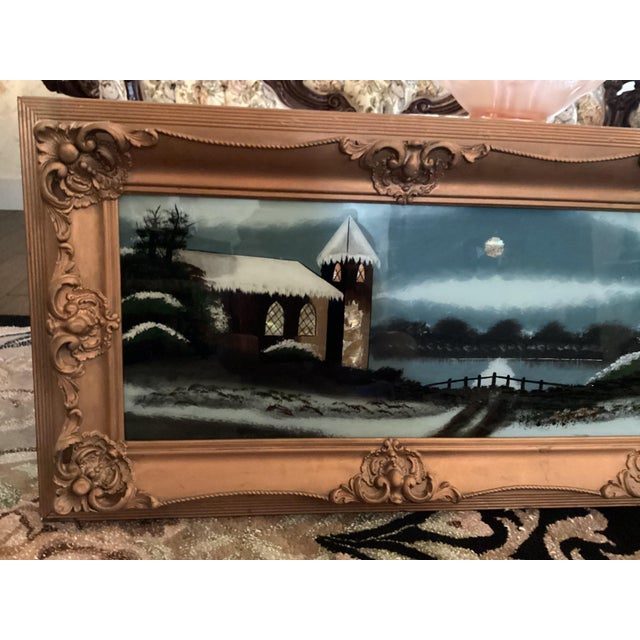 The product is an antique large fancy frame with a reverse-painted picture of a Catholic Church at an evening Mass out...