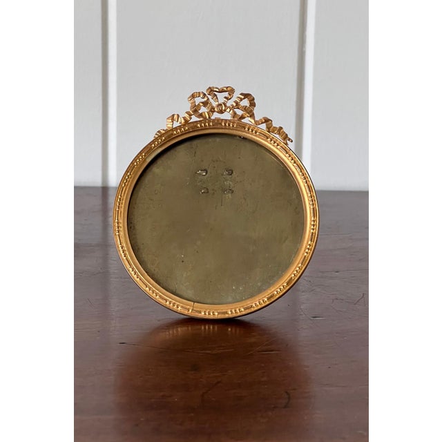Petite antique French brass tabletop frame featuring an elegant bow detail, rich patina, and timeless charm. Perfect for...