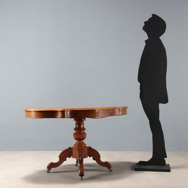 Mahogany biscuit-shaped table. Turned and carved central leg rests on four curved feet culminating in casters. Italy,...