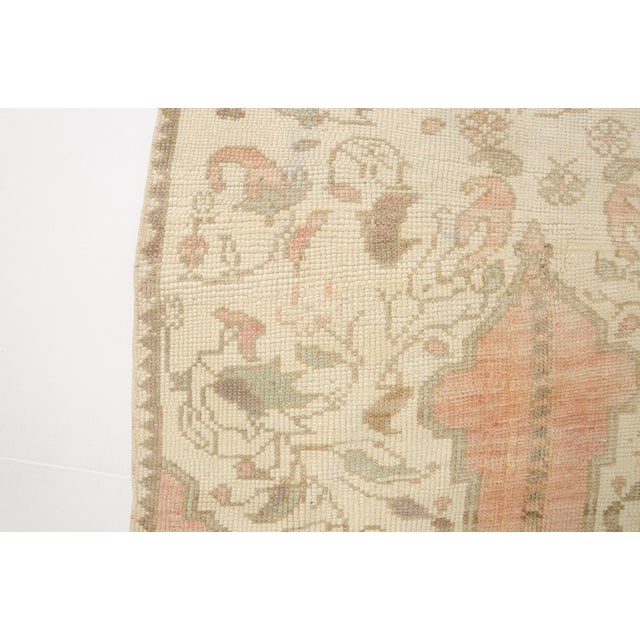 This is a vintage Turkish Oushak rug from the Mid 20th Century. The piece was hand-knotted.