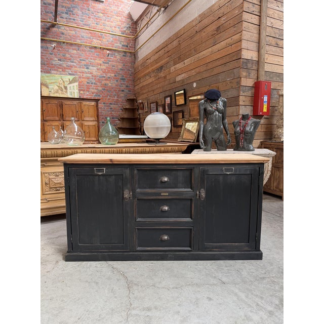 This antique sideboard has been fully restored. It features a black-patinated body and a raw wood top. It has two large...