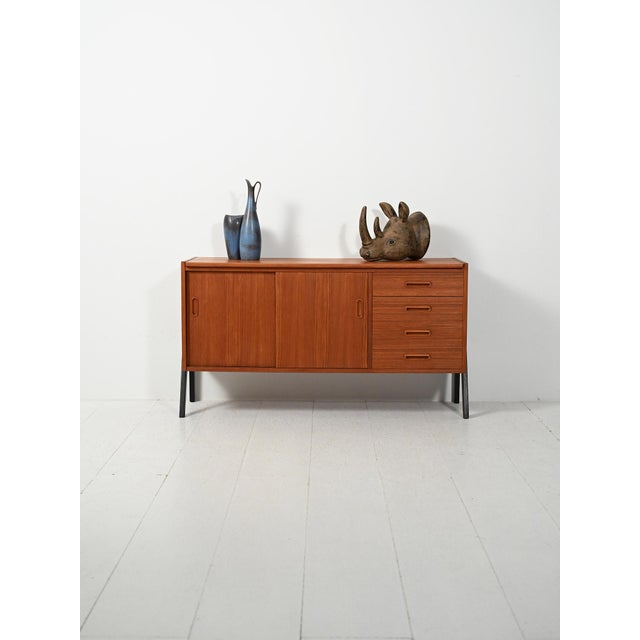 Small Scandinavian teak sideboard from the 1960s, with black lacquered exterior legs, sliding doors, and drawers with oval...