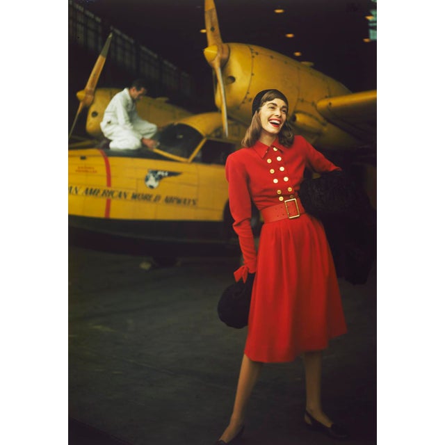 Come Fly With Me! by Toni Frissell A fashion shoot featuring a model in a red dress in front of a yellow aeroplane. (Photo...