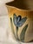 This antique Roseville 1910s ceramic pitcher adorned with bright blue tulips is a beautifully crafted piece of American-...