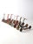 This is a collection of nine early to mid-20th century metal kick scooters, each with its own style, color, and patina....