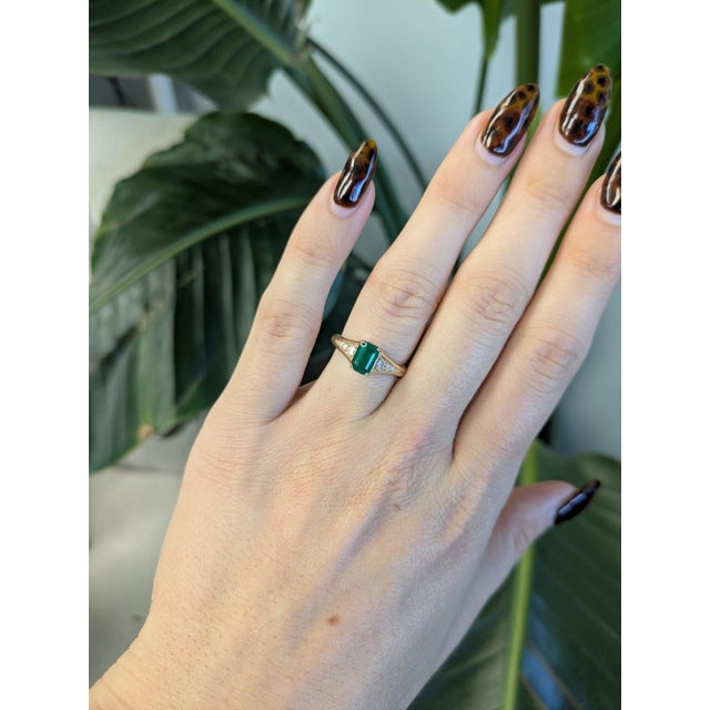 A 1.05ct zambian emerald emerald cut ring set in solid 14K yellow gold, set with ten earth mined diamonds. Emerald, the...