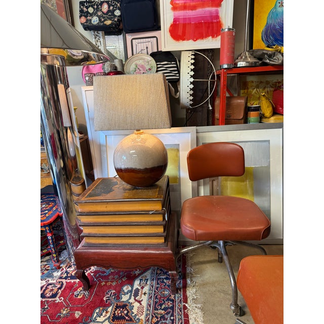 This modern accent lamp features a ceramic base finished in an earthy terracotta rust that transitions into a crackled...
