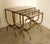 Gorgeous set of (3) patinated brass and smoked glass nesting tables in excellent condition. These tables feature Art Deco...