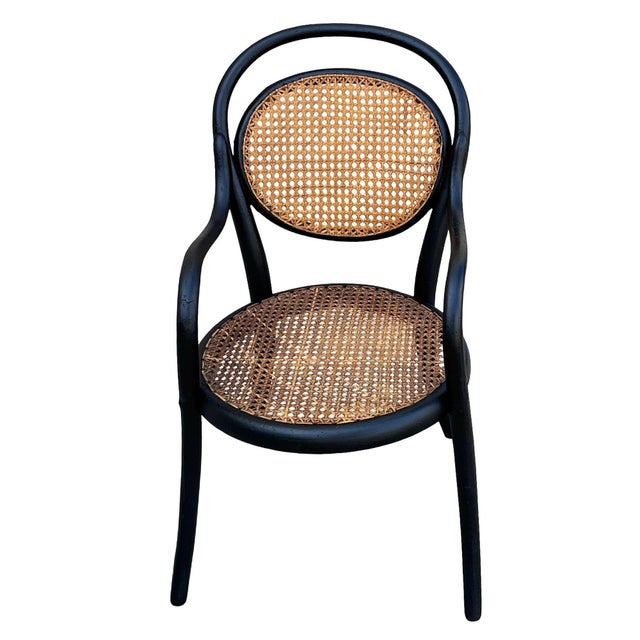 Children's size Thonet number 16 oak armchair features an elegant, sculptural frame crafted from warm-toned bentwood with...