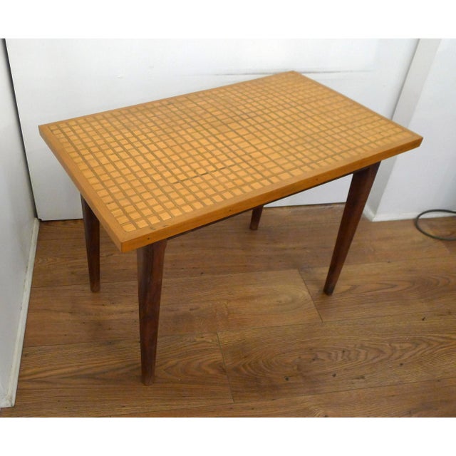 Mid-century coffee table with graphic marquetry. Rectangular shape, tapered/splayed legs in dark wood, lighter wood top...