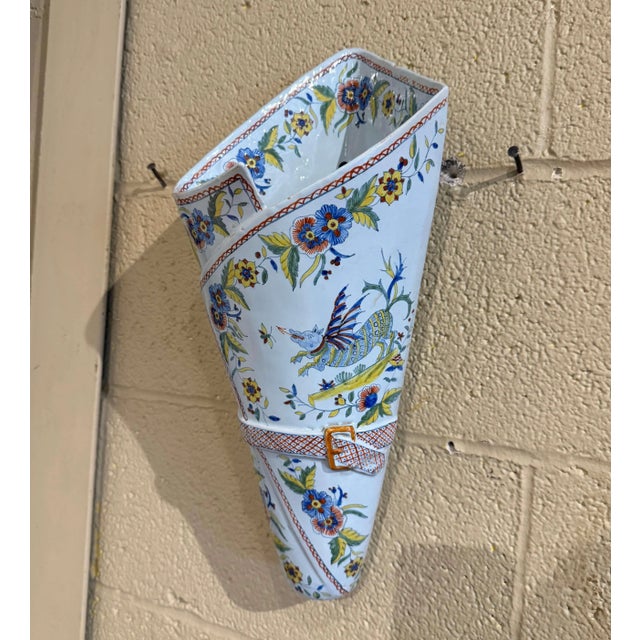 Shaped to resemble a folded bouquet holder secured with a decorative belt and buckle, this unusual antique French faience...
