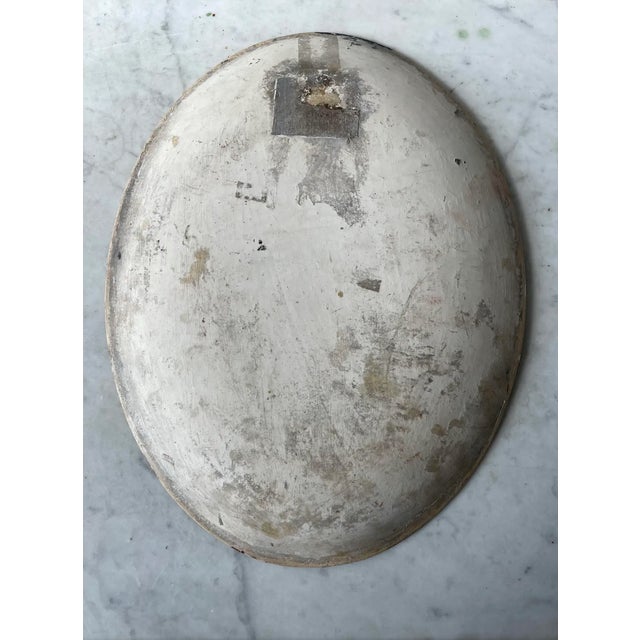 Beautiful hand painted hanging plate with the image of woman holding a basket by water as she leans on a stone wall. Oil...