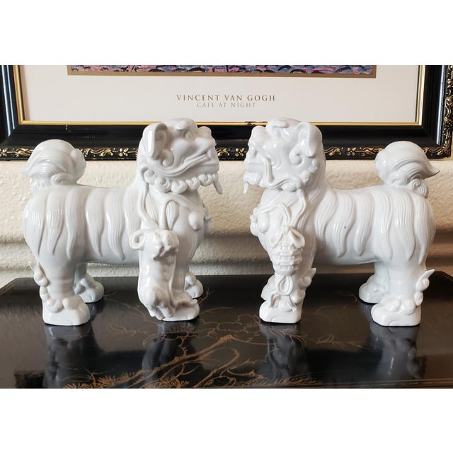 A striking pair of mid-century Japanese 'Blanc de Chine' white porcelain standing guardian lion (Foo Dog) statues....