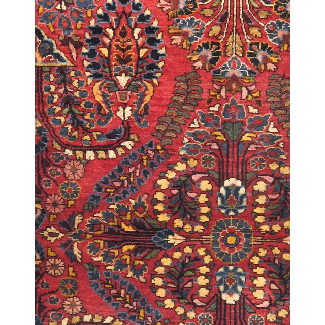 An antique Persian Sarouk rug from western Iran, featuring an elaborate floral composition with stylized palmettes,...