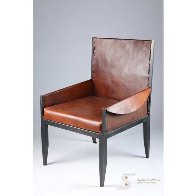 A refined custom chair in the style of Jean-Michel Frank, upholstered in cognac vegan leather on a clean dark steel frame....