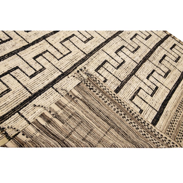 Beautiful Moroccan style handmade wool rug with a beige and brown field. This Modern rug has black and brown accents and...