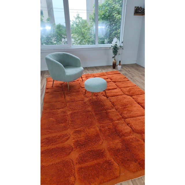 A warm terracotta-orange Moroccan rug with a hand-carved relief that breaks the deep pile into soft brick-like panels....