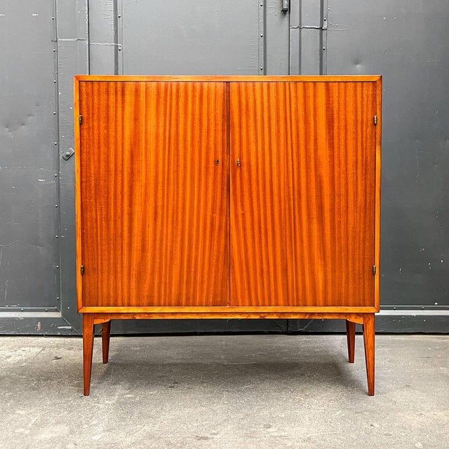Product. Small highboard. Style. Mid-century, 1960s. Material. Mahogany veneer, partially solid wood. Features. Two doors,...