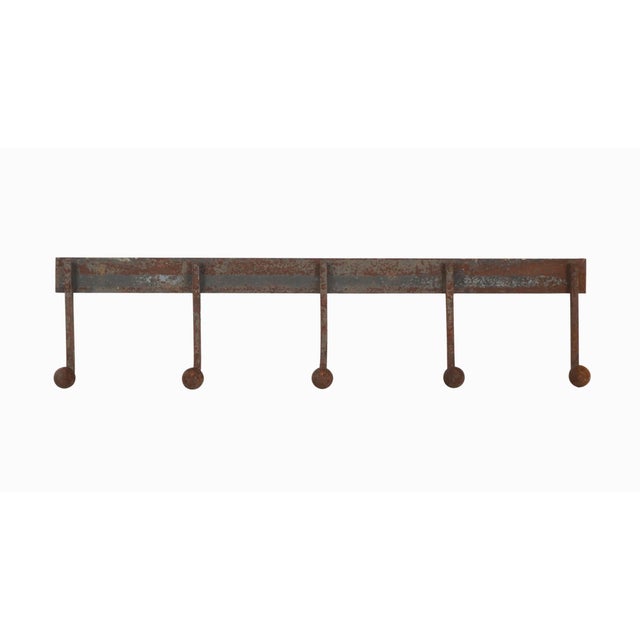 Industrial style wall hook rail with five peg hooks. It is made of wrought iron with a distressed rusted finish. It has a...
