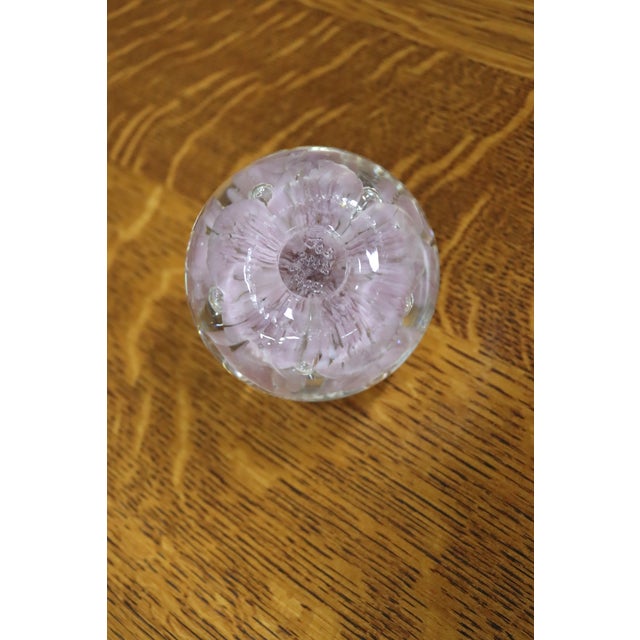 Handcrafted art glass paperweight featuring a delicate lampworked bouquet of soft pink flowers encased in clear crystal....