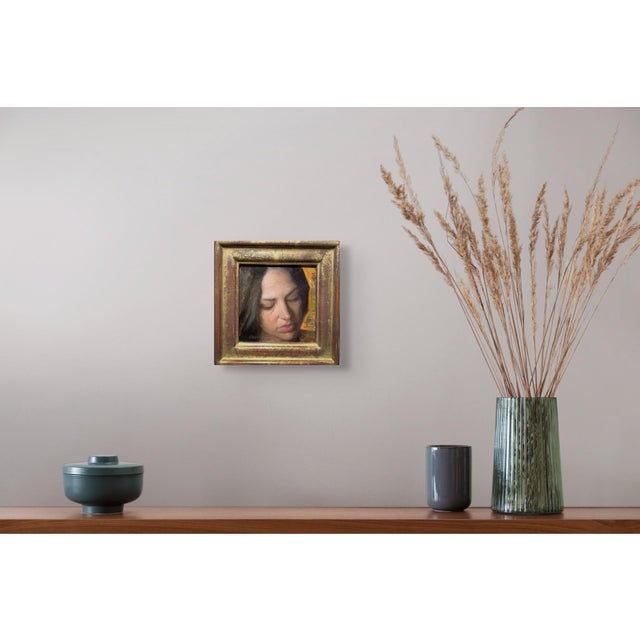 This artwork depicts a woman in a moment of introspection, her features softly illuminated by warm tones that evoke a...