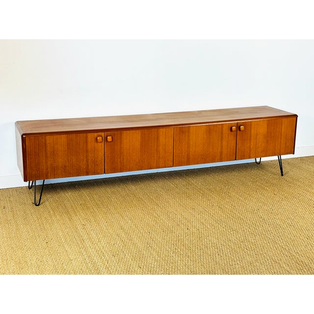 A stunning low sideboard in scandinavian design, dating from the 1960s, crafted from teak wood with warm tones and an...