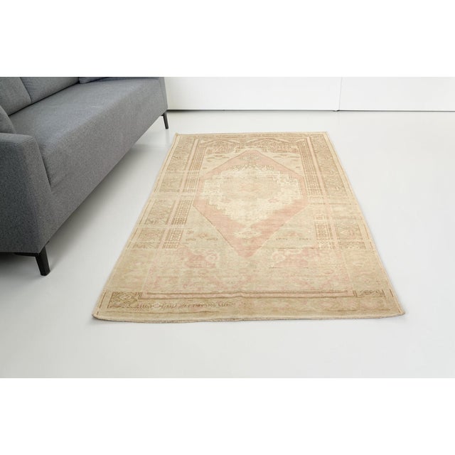 This is a vintage Turkish Oushak rug from the Mid 20th Century. The piece was hand-knotted.