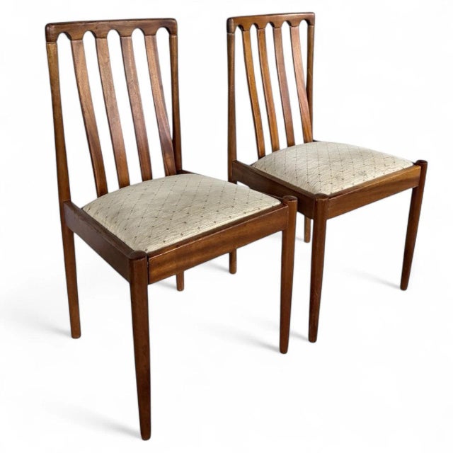 This pair of mid century teak dining chairs offers timeless style and comfort, perfect for enhancing your dining space...