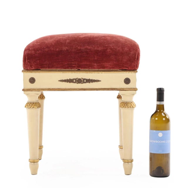 A refined trio of stools, each featuring a white-painted and giltwood frames with classical carved details and turned...