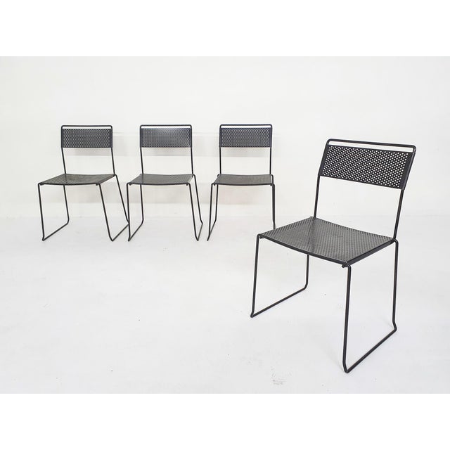 Black metal dining tables with perforated seating and back. One chair has been re-painted black.