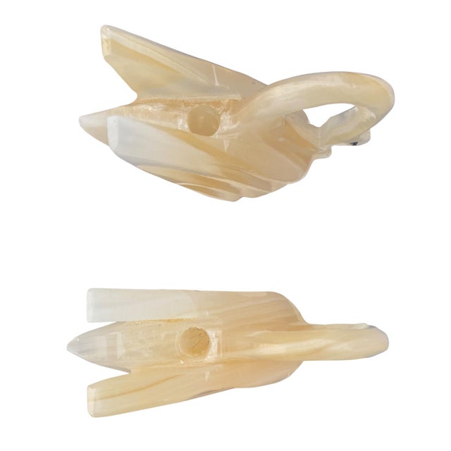 Elegant pair of hand-carved stone swan sculptures, crafted in softly banded onyx/alabaster tones and mounted on oval stone...