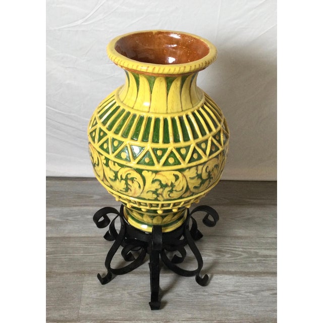 A vibrant yellow and green Italian earthen ware vessel with hand forged wrought iron stand. The glaze is hand decorated...