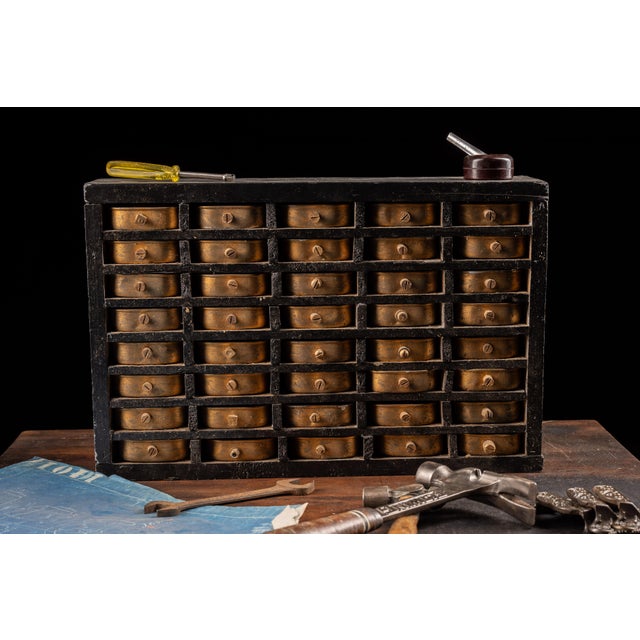 This folk art cabinet was made by hand and features forty drawers made from gold colored tin that measure 4.25" in width,...