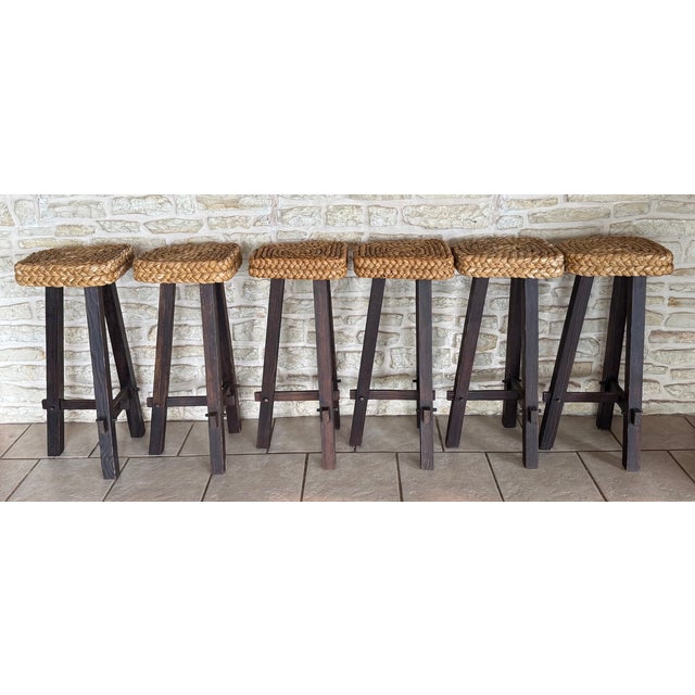 A set of six three legged or tripod French bar stools with braided hemp seats, attributed to Adrien Audoux and Frida Minet.