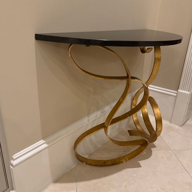 The console table is identified as the Cyan Design Ribbon Console Table, featuring a distinctive gold, ribbon-shaped metal...