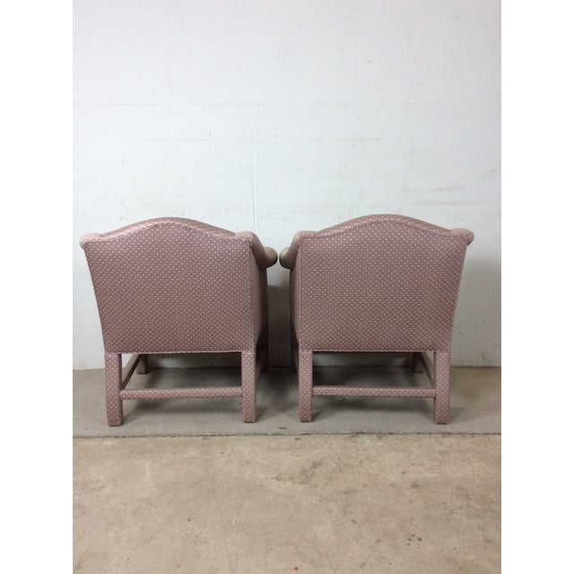This pair of vintage upholstered chairs feature pink polka dot upholstery throughout, low back and rounded arm rests with...