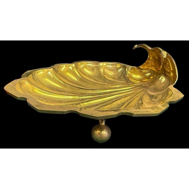 This is a 1970s heavy cast brass shell form footed serving dish or catchall. It was manufactured by Decorative Crafts. It...