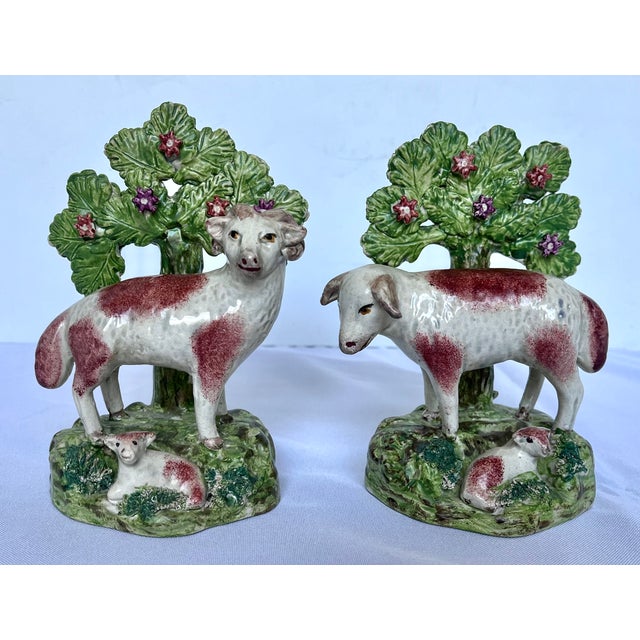 A exceptional, mirrored pair of early 19th-century English pearlware pottery pastoral figures featuring a ram and a ewe,...