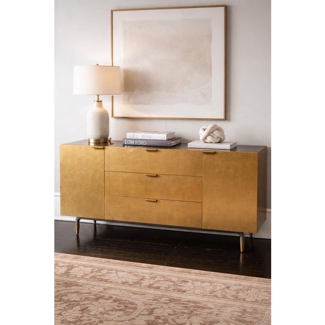 A 1960s aurum-finished media cabinet defined by clean mid-century lines, original brass hardware, and timeless...