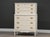 A painted white tall dresser with brass color drawer pulls. Minor indentations and wear on paint with age and use. Circa...