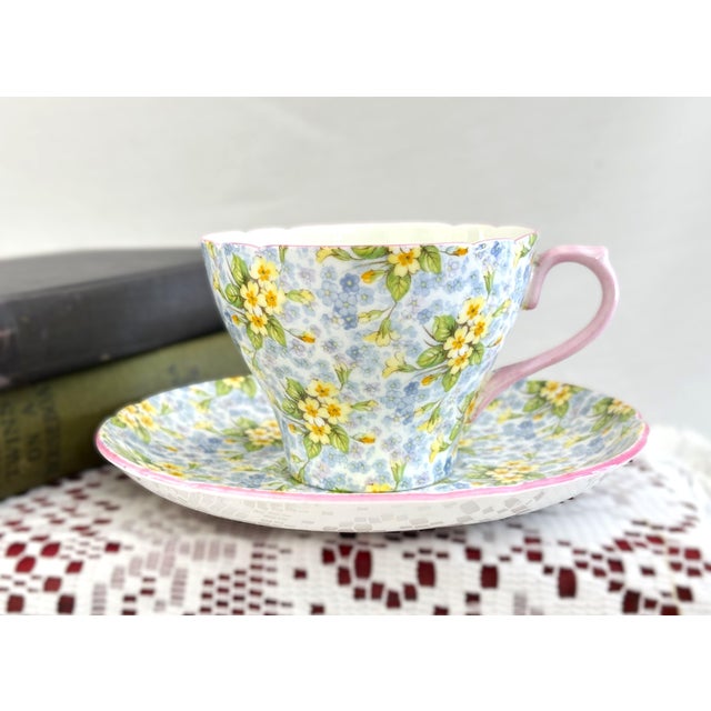 This vintage fine bone china teacup and saucer set was crafted by Shelley in Staffordshire, England. It features the...