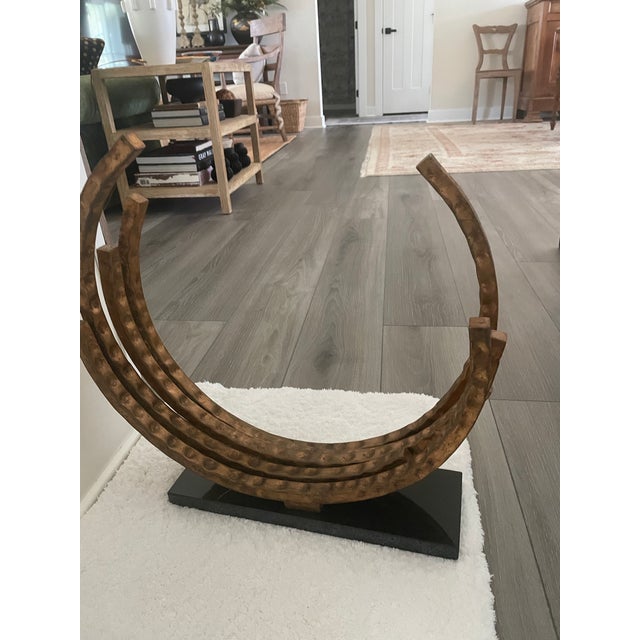 One gilted metal sculture mounted on a black marble base.. It is composed of a series of five open half circles connected...