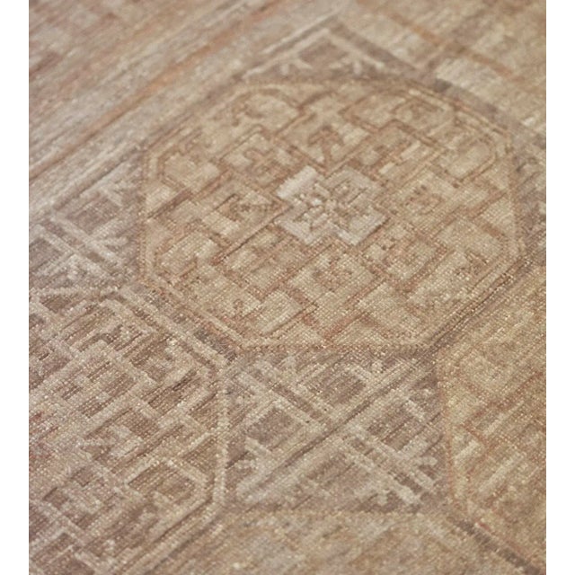 This revival Khotan rug features a field with eight horizontal rows of five squares containing a buff-brown and shaded...