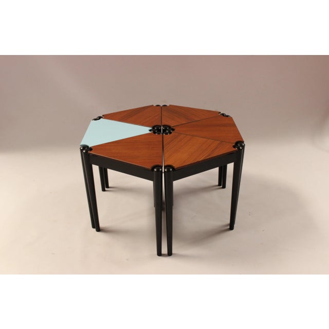 This coffee table consists of six triangular side tables in teak and blue-lacquered wood. The piece stands on black-...