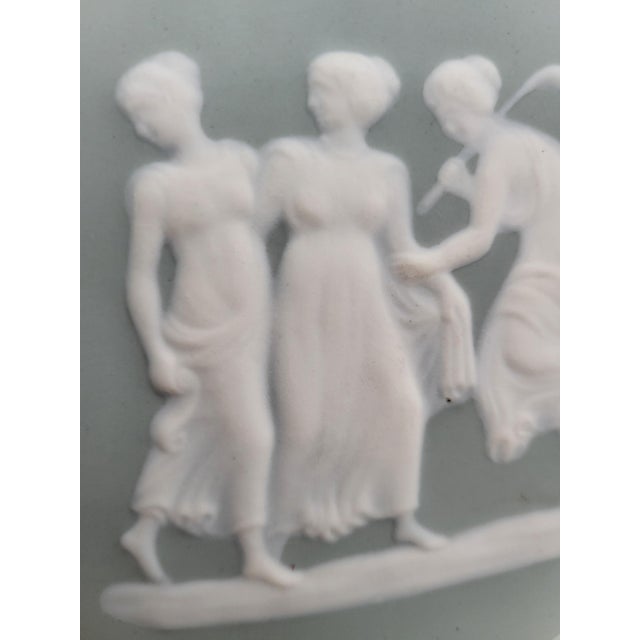 This mid-century round french porcelain plaque features an elegant, high-relief neoclassical cameo depicting the "three...
